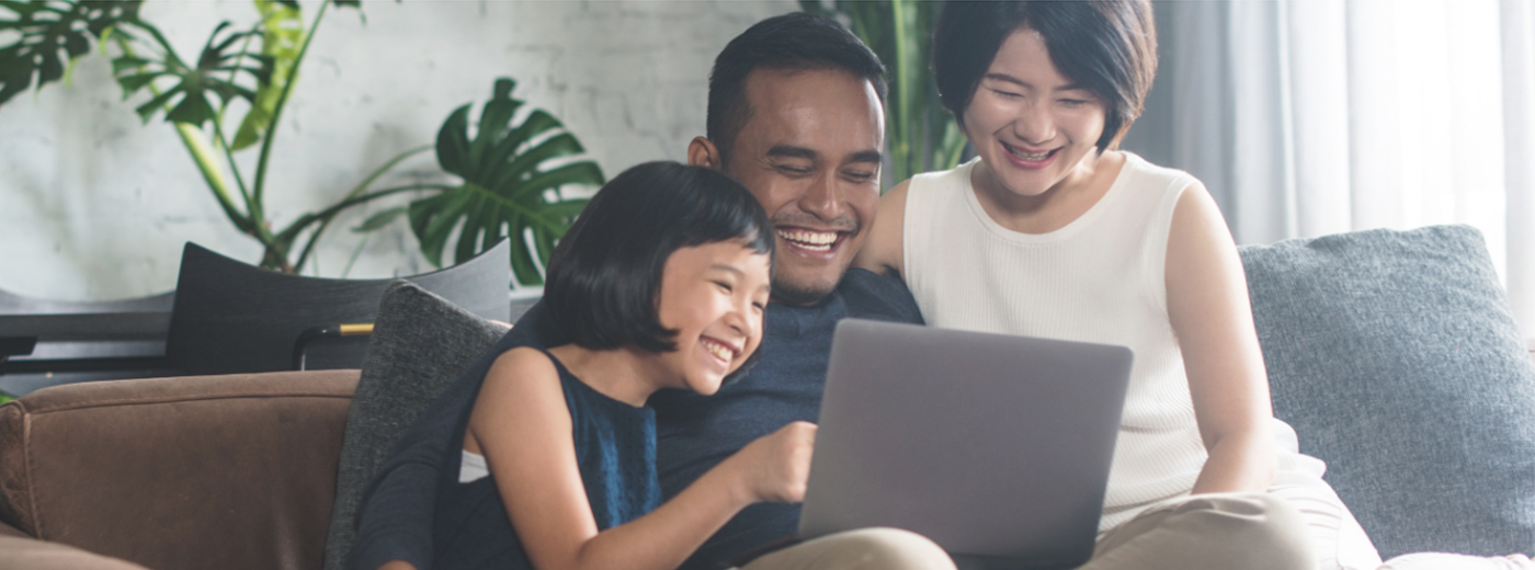 Family laughing together while looking at computer